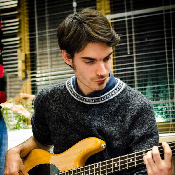 Foto a colori con primo piano di un ragazzo concentrato mentre si sta esibendo con la chitarra elettrica